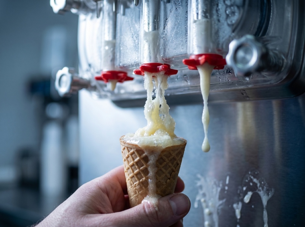 Warning Signs Your Soft Serve Machine Is About to Fail (and How to Act Early) 3 A close-up showing a malfunctioning commercial ice cream maker dispensing runny, soupy, and icy soft serve into a waffle cone, demonstrating severe texture, cooling, and freezing consistency issues.